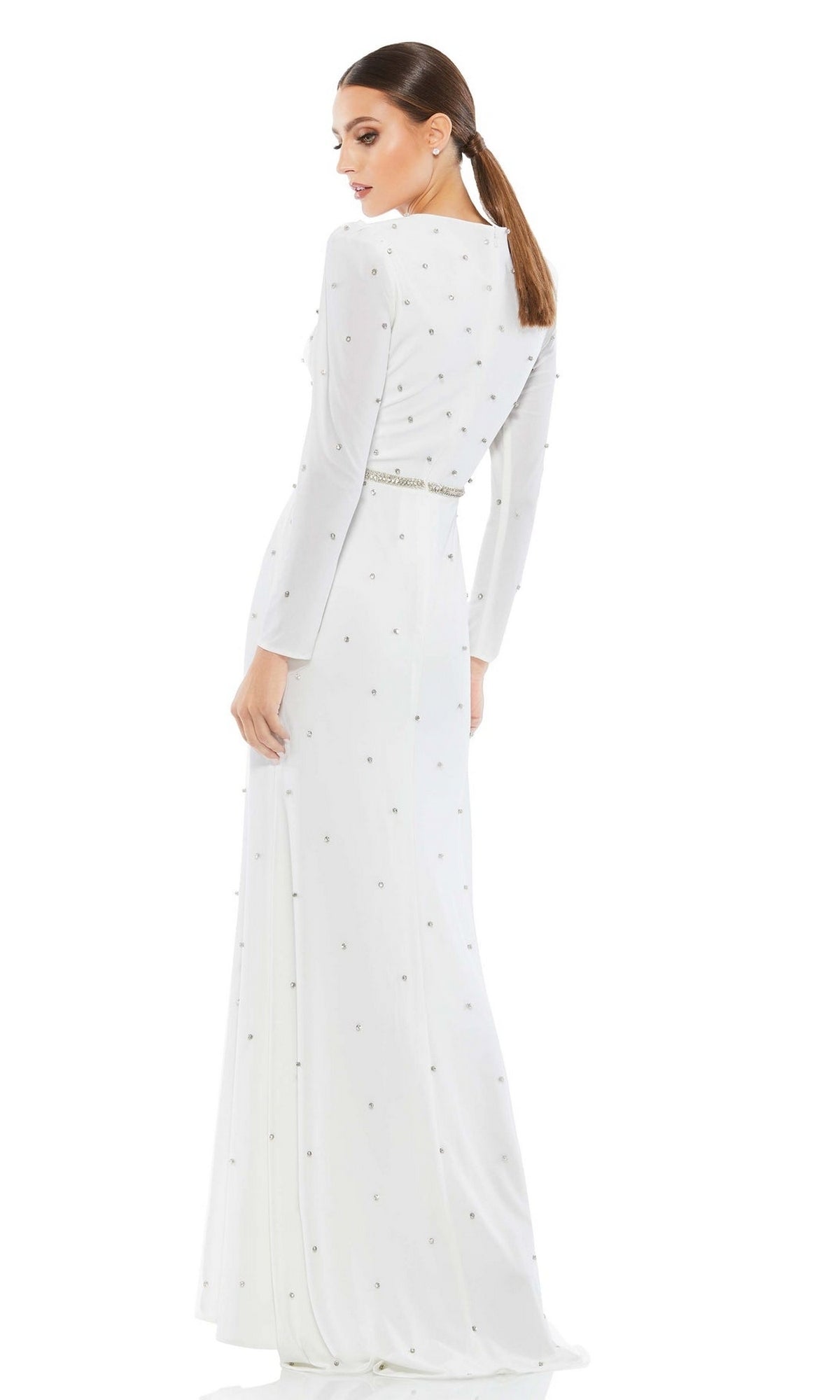 A woman wearing the Long Formal Dress 67874 by Mac Duggal, featuring long sleeves and subtle embellishments, stands facing away and looks over her shoulder.